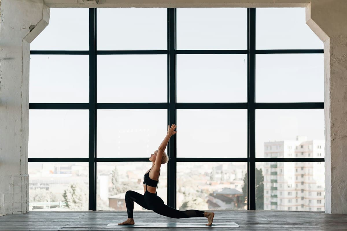 ผู้หญิงทำท่าโยคะข้างหน้าต่างบานใหญ่