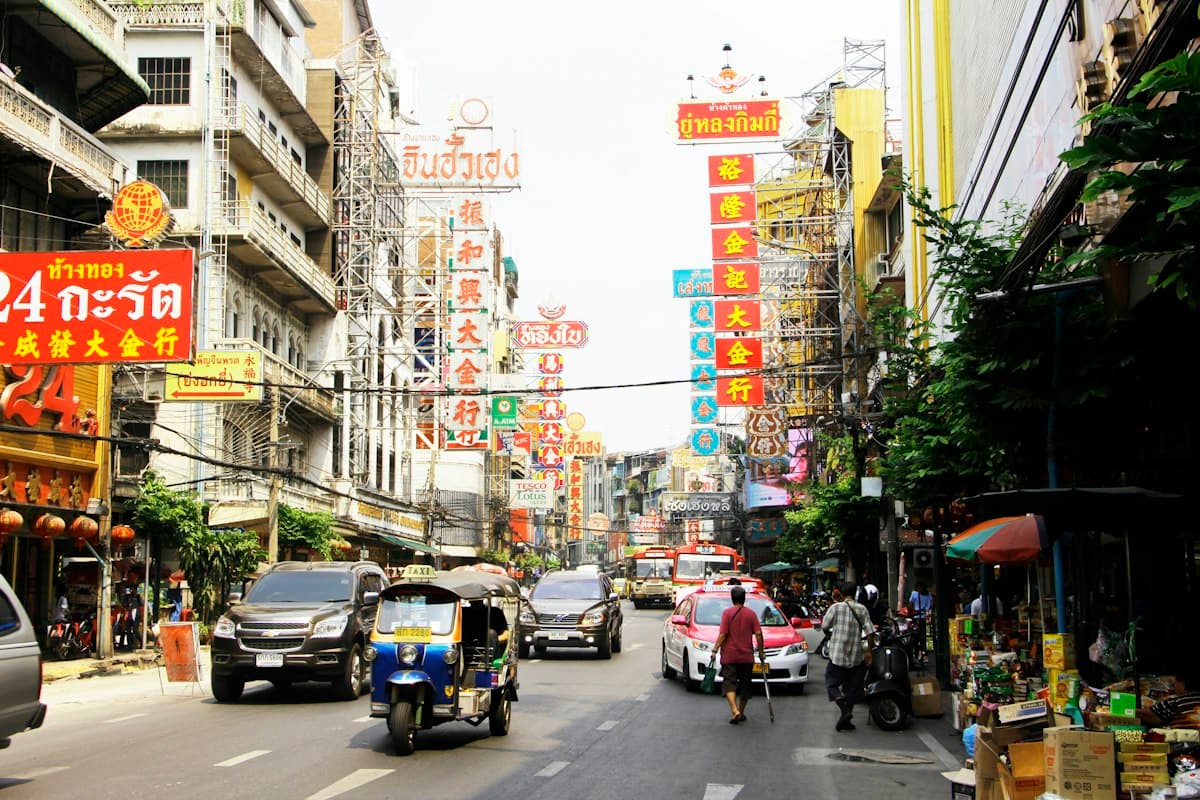 ถนนในกรุงเทพที่มีป้ายร้านค้าภาษาไทยและรถตุ๊กตุ๊ก